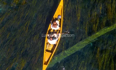 Sepasang kekasih dengan perahu di Danau dengan air jernih sampai terlihat tumbuhan bawah air