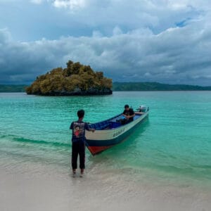 Dua orang pria dengan perahu di pantai pasir putih Oyama
