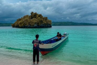 Dua orang pria dengan perahu di pantai pasir putih Oyama