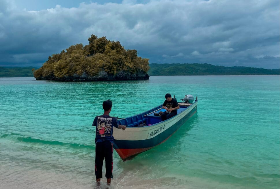 Dua orang pria dengan perahu di pantai pasir putih Oyama