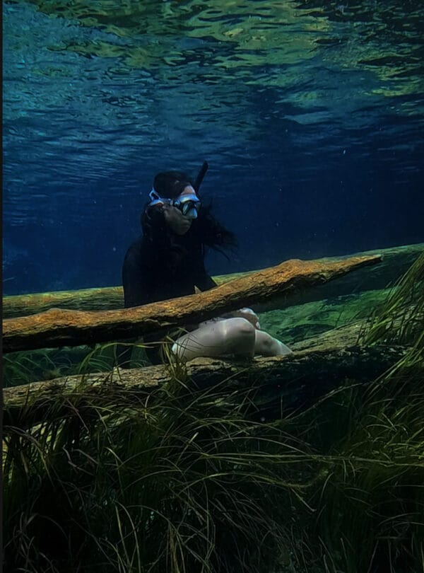 Snorkeling in waters of Banggai with a clear, spring-fed body of water with abundant underwater plant life and submerged logs