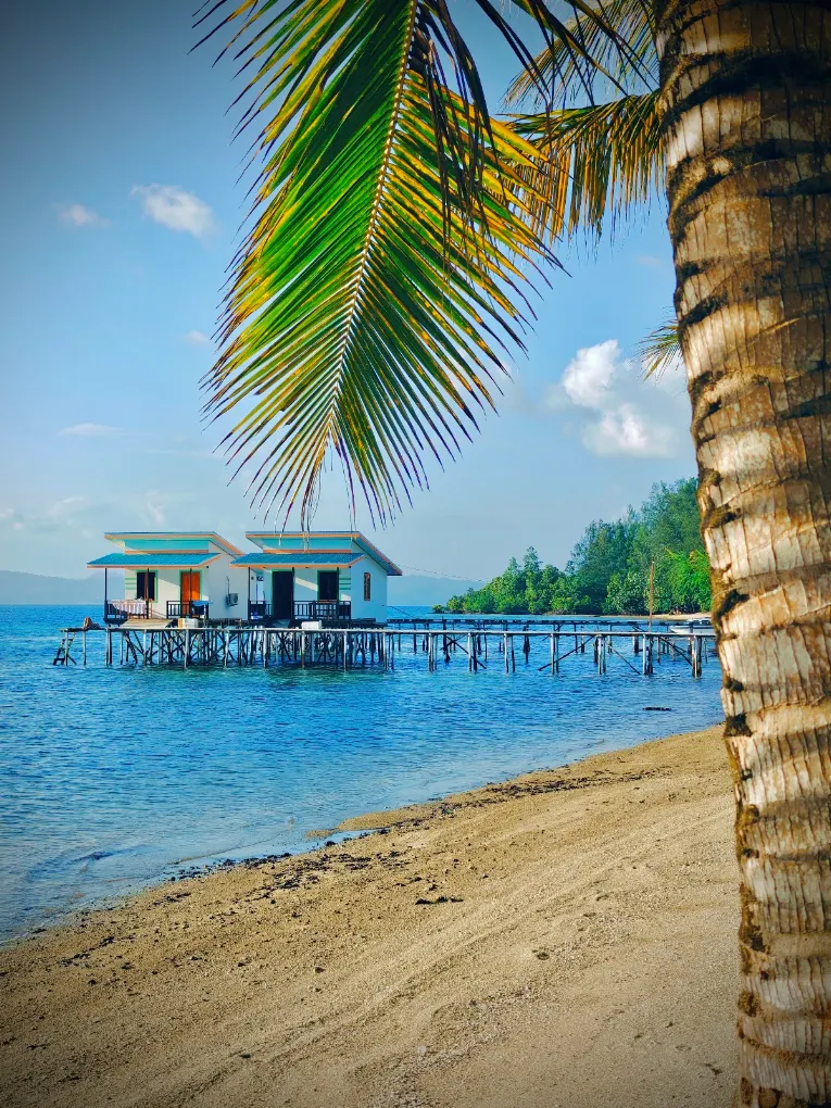 Bungalow di atas air dengan dermaga kayu dan pantai pasir putih di Kepulauan Banggai