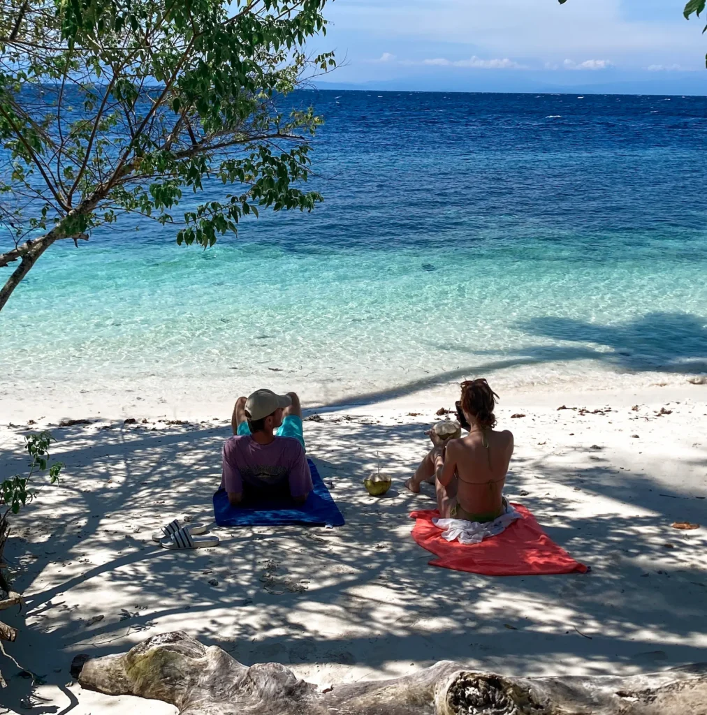 Les touristes se détendre au Kilo 5 Plage de Luwuk avec clair teinté de vert d'eau et les montagnes en toile de fond