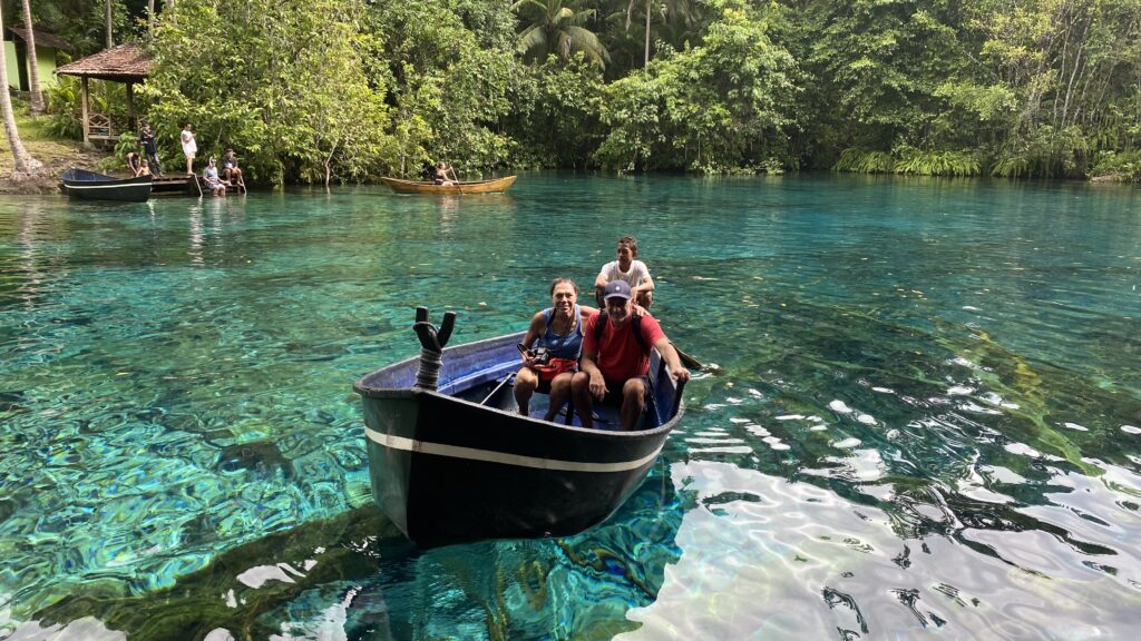 Travelers in boat at Paisu Pok Lake with crystal clear water showing visible lake floor and fish in Banggai Islands Sulawesi Indonesia