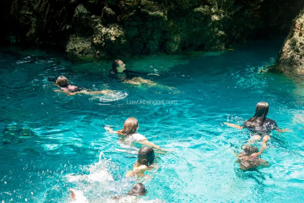 Beberapa orang berenang di air jernih berwarna biru toska