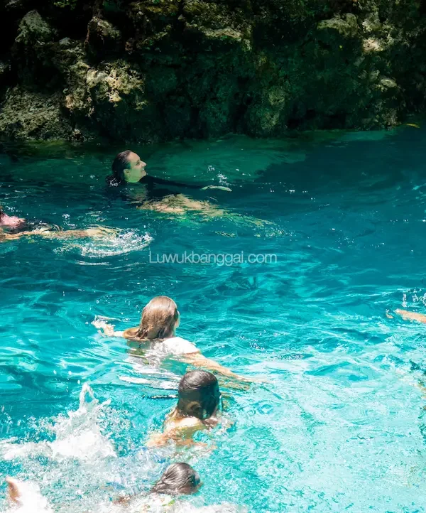 Beberapa orang berenang di air jernih berwarna biru toska