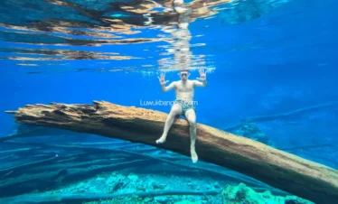 Seorang pria santai menyelam di bawah Danau berair biru
