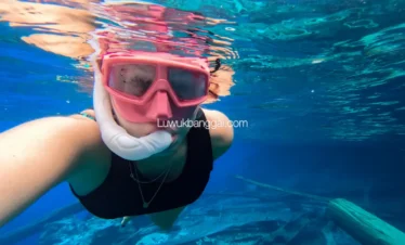 Seorang wanita snorkling di danau berair biru jernih