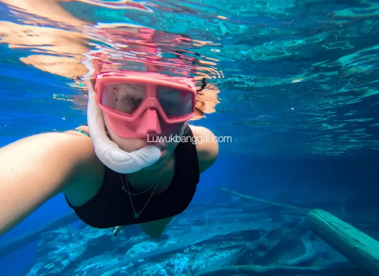 Seorang wanita snorkling di danau berair biru jernih