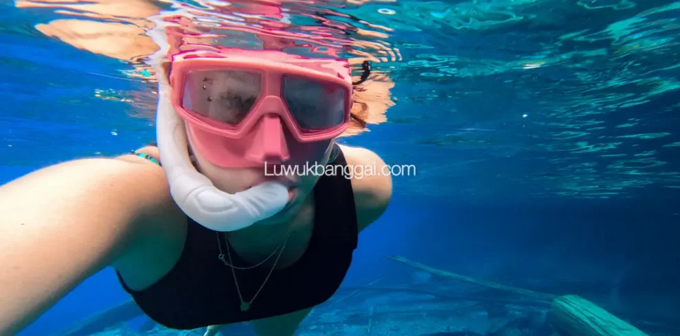 Seorang wanita snorkling di danau berair biru jernih