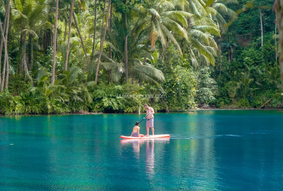 Twee reizigers op een supboard op het heldere, turquoise water van het Paisu Pok-meer