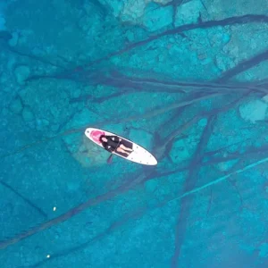 Woman relaxing on a paddle board in clear blue Paisupok lake