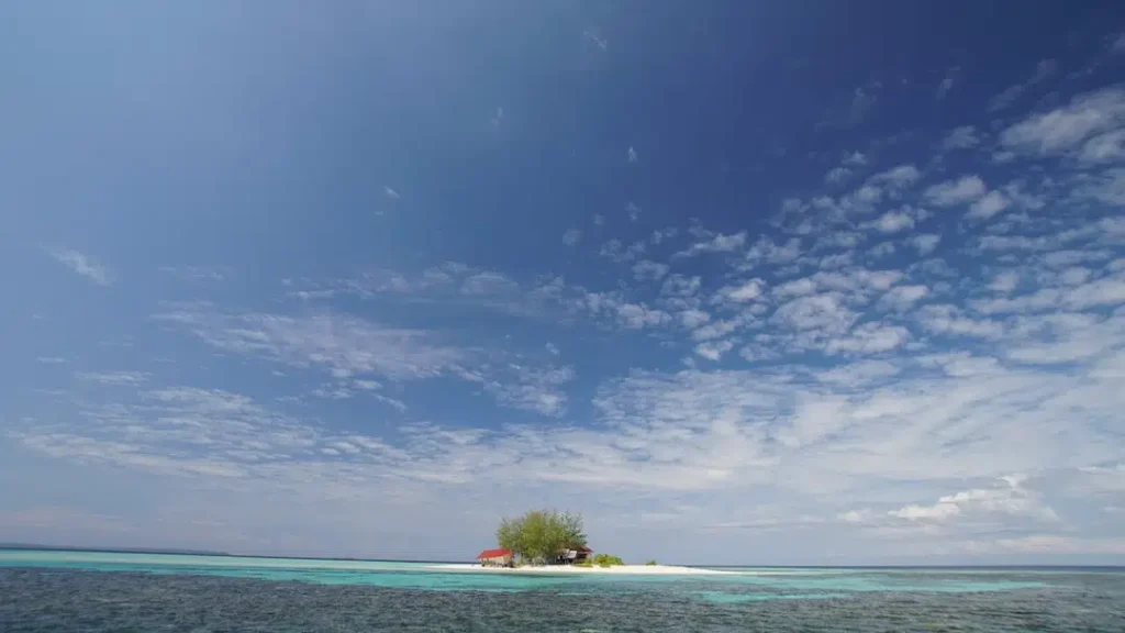 Aerial view of Pulau Tinalapu in Luwuk Banggai featuring a tiny tropical island with white sand and turquoise water.