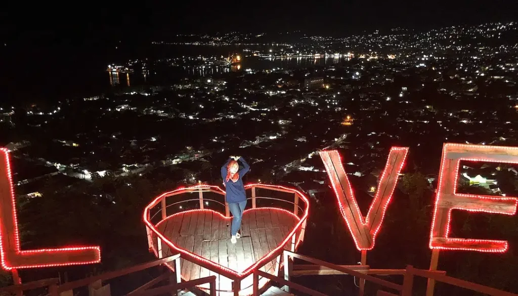 Night time city view of Luwuk from Bukit Kasih Sayang featuring a lit up heart shaped platform and neon LOVE sign