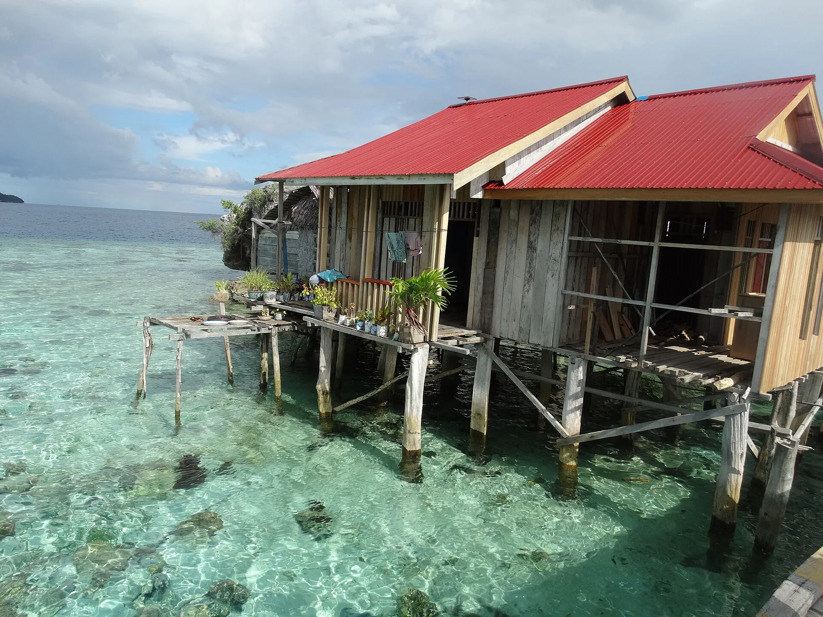 A red-roofed Bajau stilt house standing over turquoise shallows in Kabalutan