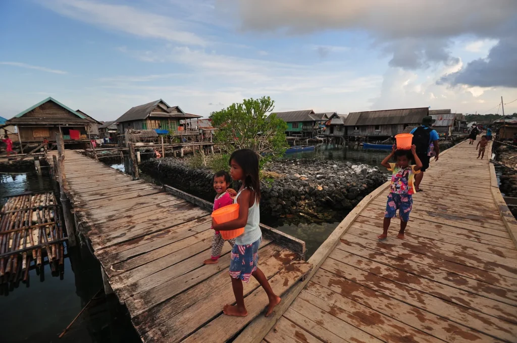 Anak-anak Bajo berjalan di jembatan kayu Desa Sampela, Wakatobi