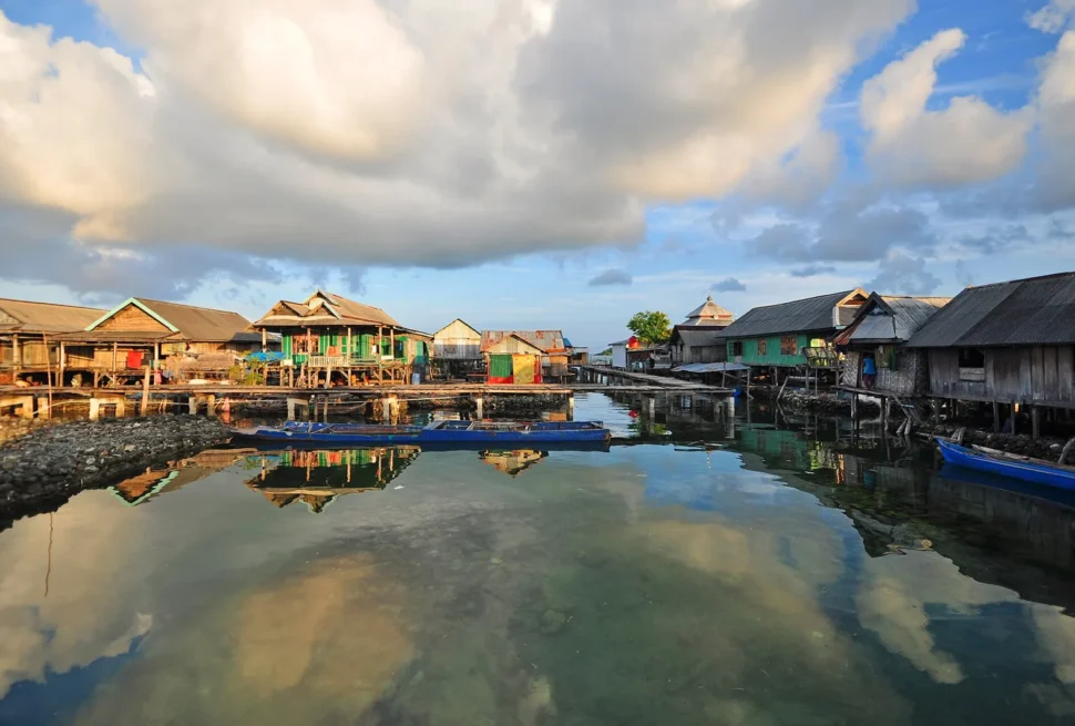 Bajo-paalwoningen weerspiegeld in kalm water in het dorp Sampela, Wakatobi