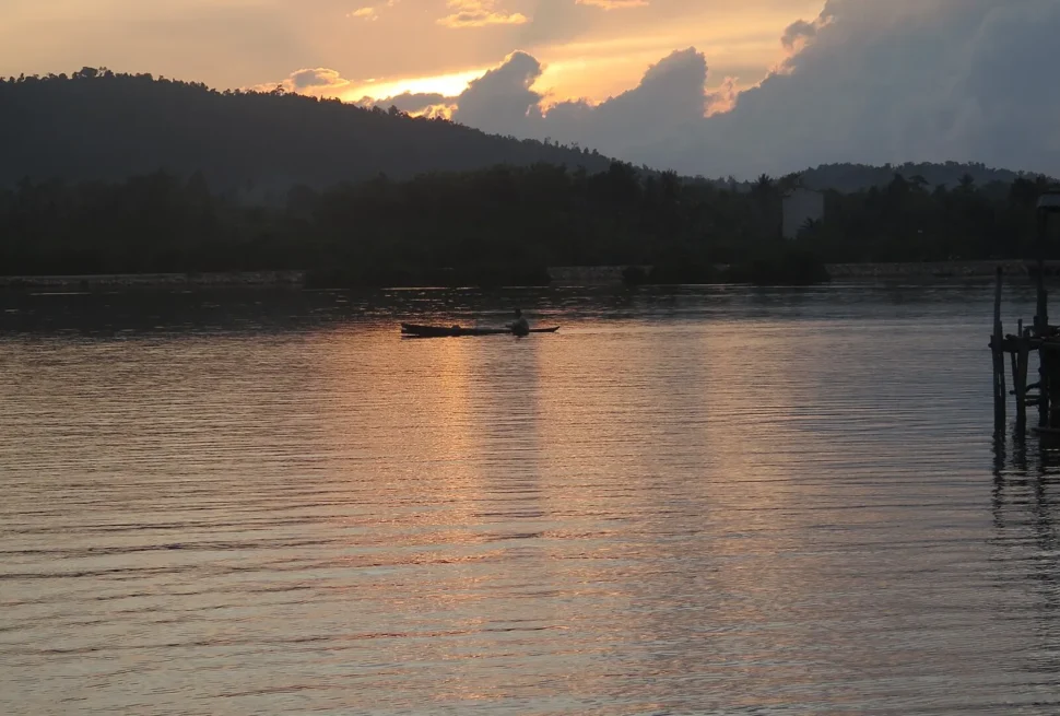 Lelaki Bajo mendayung sampan kayu saat senja di Jaya Bakti, Pagimana, dekat Luwuk