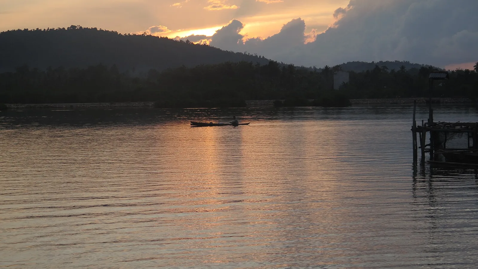 A Bajo man paddling a wooden canoe at dusk in Jaya Bakti, Pagimana, near Luwuk