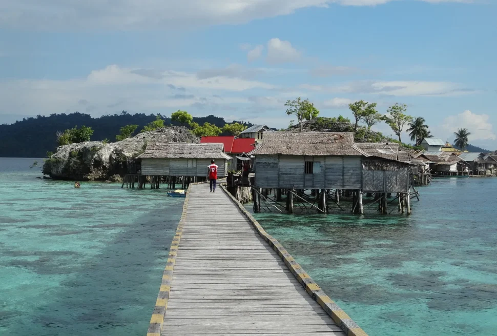 Wooden walkway leading to Bajau stilt houses over clear water in Kabalutan, Togian Islands