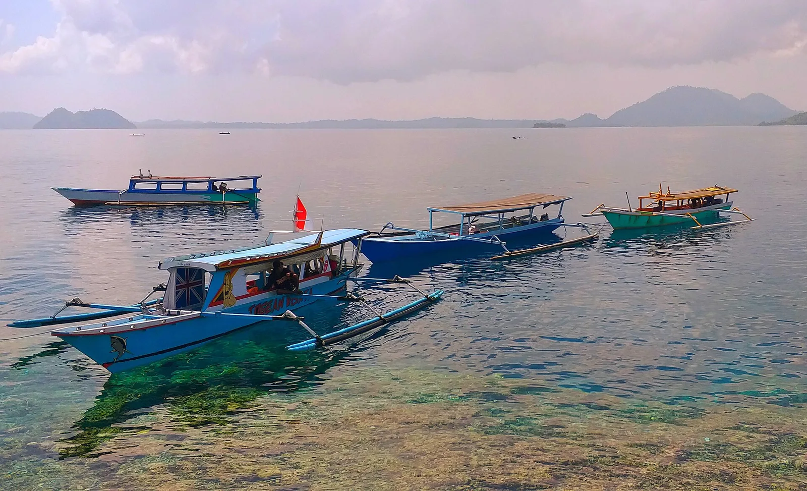 Bateaux en bois amarrés au-dessus d’une eau limpide sur le récif de Karang Atol, îles Togian