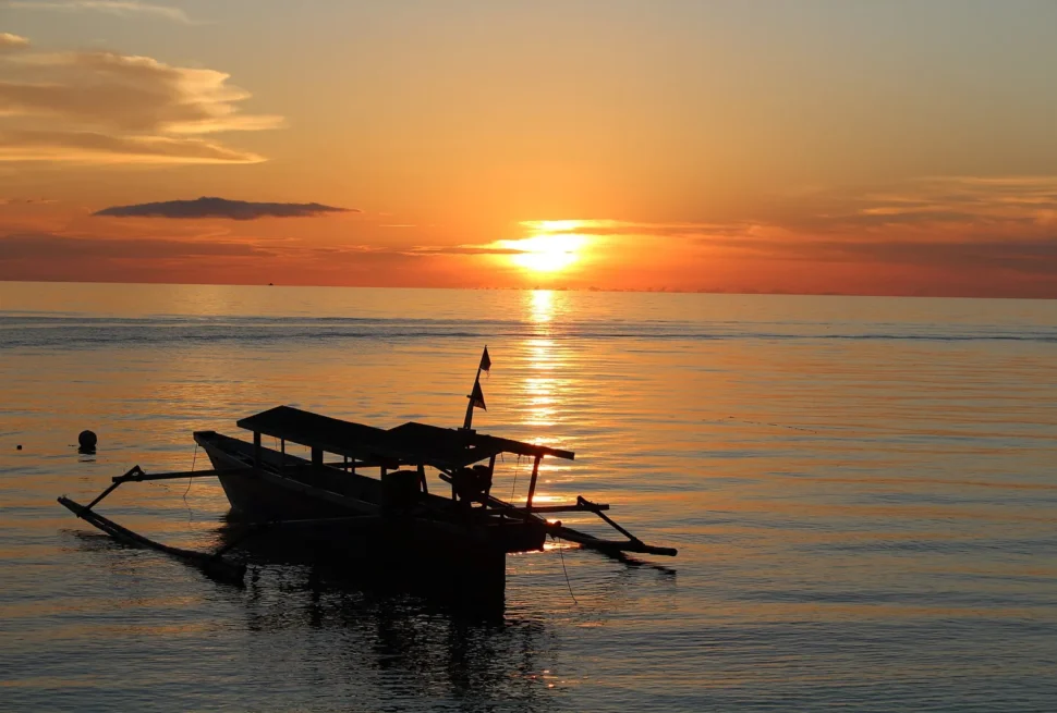 Auslegerboot im Gegenlicht des Sonnenuntergangs auf den Togian-Inseln