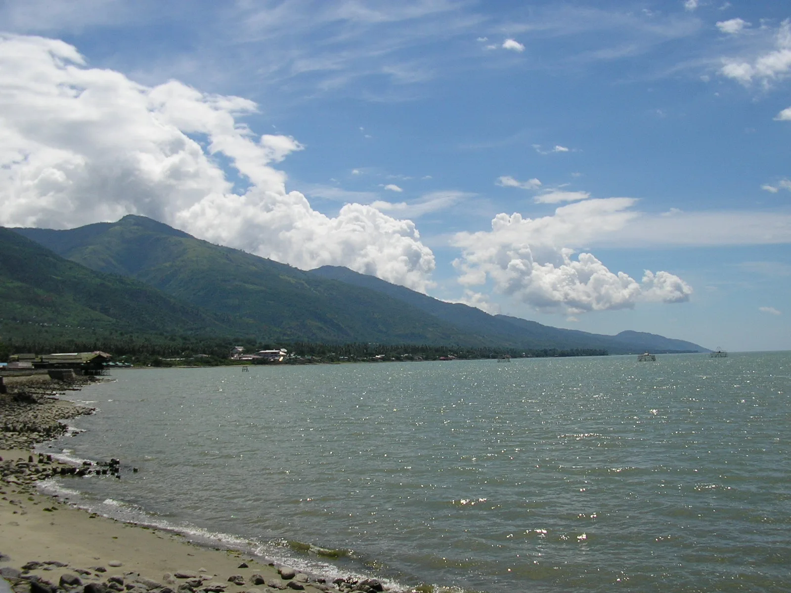 Pantai berbatu di Teluk Palu dengan pegunungan di latar belakang